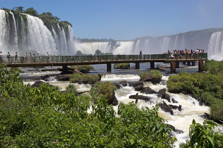 Footbridge and tourists at the Iguazu Falls, from the Brazil side. Iguazu Falls are waterfalls of Iguazu River on the border of the Argentine province of Misiones and the Brasilian state of Paranaの写真素材