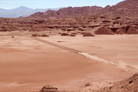 Cars are crossing the Desierto del Diablo, Devil Desert, landscape in Puna de Atacama, Argentina. It is a giant desolate place. This red landscape seem from the another planet.の写真素材