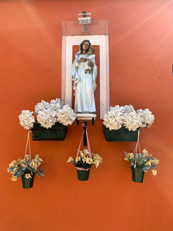 Little Madonna statue on the wall of the brightly colored houses at Burano, island in the Venetian Lagoon in northern Italy, Venice, Italy. Burano is a island near Torcello at the northern end of the lagoon. The primary economy is tourism.の写真素材