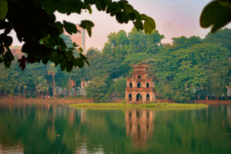 The Turtle Tower at Hoan Kiem Lake in Hanoi, Vietnam, captured during a tranquil moment with the morning light reflecting off the water.の写真素材