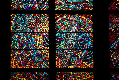 A close-up of a colorful stained glass window, depicting abstract religious imagery with vibrant hues of red, blue, yellow, and purple.の写真素材