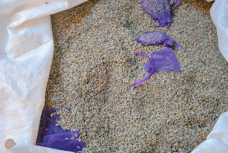 Dried lavender buds in bulk with small purple sachets on display, ready for packaging or sale.の写真素材