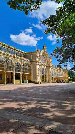 Vertical view of the historic colonnade in Marianske Lazne, Czech Republic, with blue sky and leafy framing.の写真素材