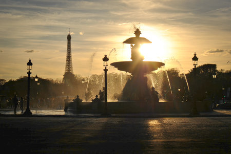Silhouette of the Fontaine des Mers with water sprays at sunset on Place de la Concorde in Paris, with the Eiffel Tower visible in the background.の写真素材