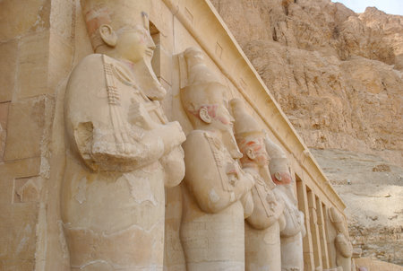Row of colossal Osiride statues of Pharaoh Hatshepsut with crossed arms, located at her mortuary temple in Deir el-Bahari, Egypt, carved into the cliffside.の写真素材