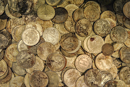 Old silver and bronze coins from various countries in a close-up view. A mix of vintage currency with signs of age and oxidation.の写真素材