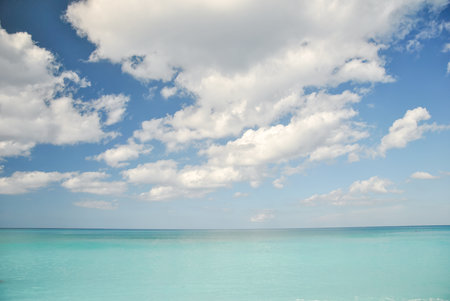 Blue sky with white clouds over calm turquoise sea on a sunny day.の写真素材