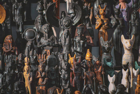 Colorful collection of small Egyptian statues representing ancient gods, pharaohs, and mythological animals, displayed tightly packed in a souvenir shop.の写真素材