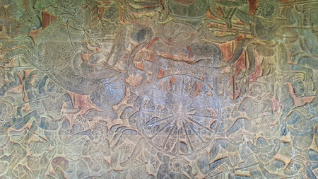 Ancient bas-relief from Angkor Wat temple depicting a mythological battle scene with warriors, chariots and divine creatures. Khmer Empire, Cambodia.の写真素材