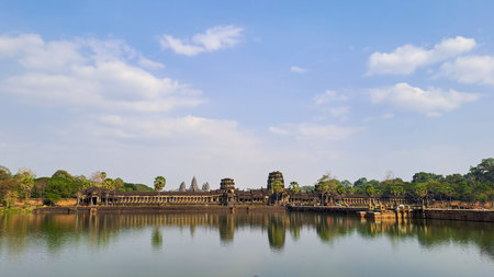 View of Angkor Wat temple reflected in water under a blue sky, taken from across the moat in Siem Reap, Cambodia.の写真素材