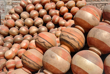 Close-up view of a large pile of traditional terracotta water pots with red and beige stripes, some decorated with black painted patterns.の写真素材