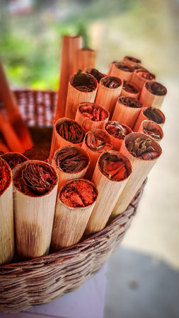 Close-up of traditional betel nut parcels in bamboo tubes, displayed in a woven basket in Cambodia. Chewing ingredients for ceremonial or daily use.の写真素材