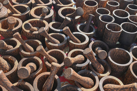Collection of handcrafted wooden mortars and pestles displayed for sale at a local market under natural sunlight.の写真素材