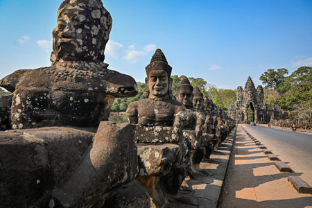 Stone statues lining the bridge at the South Gate of Angkor Thom, part of the Angkor complex in Cambodiaの写真素材