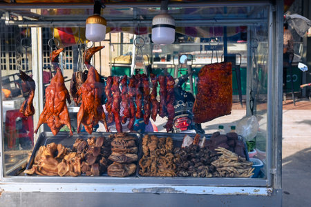 Display of roasted ducks, pork, and various cooked meats at a street food stall in Southeast Asia.の写真素材