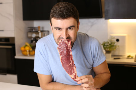 Hungry man eating raw meatの写真素材