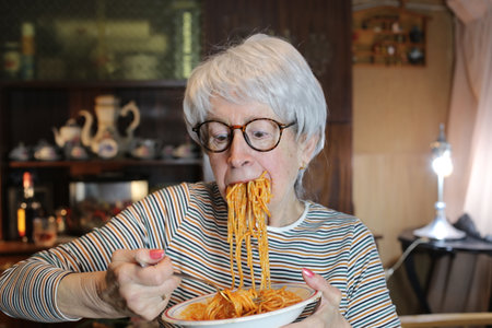 Senior woman enjoying a plate of spaghetti with tomato sauce