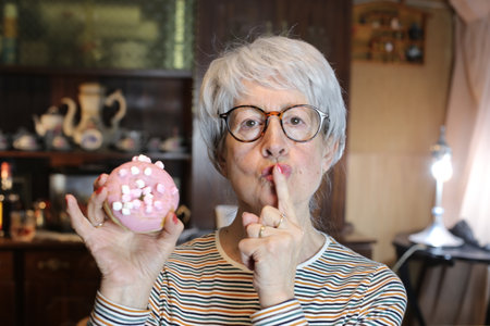 Senior woman secretly eating a doughnut