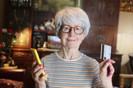 Senior woman using credit card with mobile phone