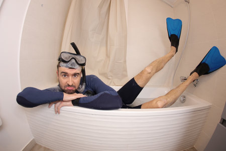 Humorous man snorkeling in the bathtub