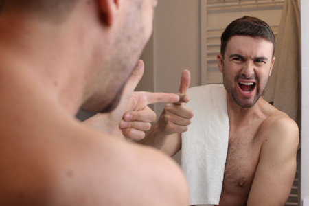 Man blaming himself in the bathroom mirror