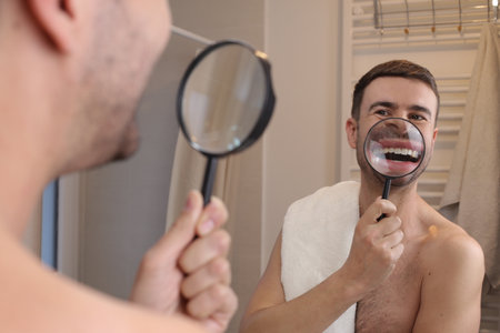 A man is analyzing his dental health with a loupeの写真素材