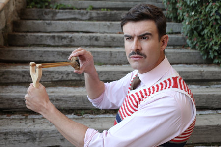 Elegant man with a vintage look using slingshotの写真素材
