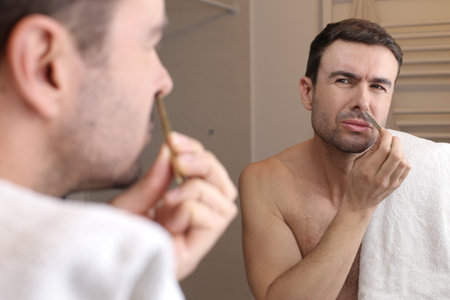 Man using tweezers to pluck nose hairsの写真素材