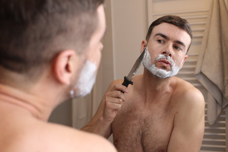 Man shaving his face with a knifeの写真素材