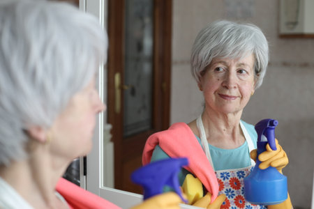 Senior woman cleaning a mirror