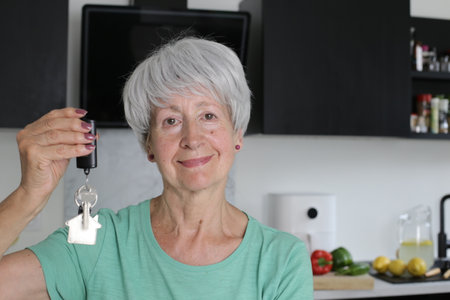 Senior woman showing the keys of her new modern home