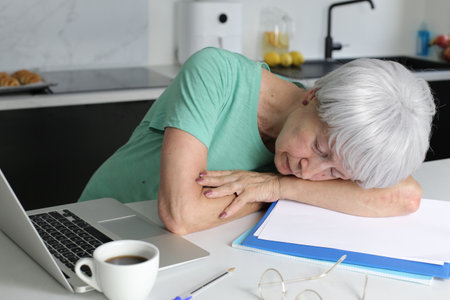 Senior woman falling sleep while doing some home office workの写真素材