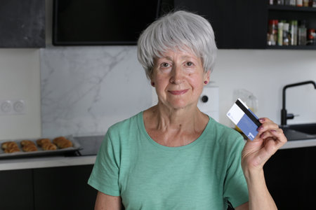 Senior woman holding credit card at home