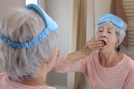 Sleepy senior woman in front of the mirrorの写真素材