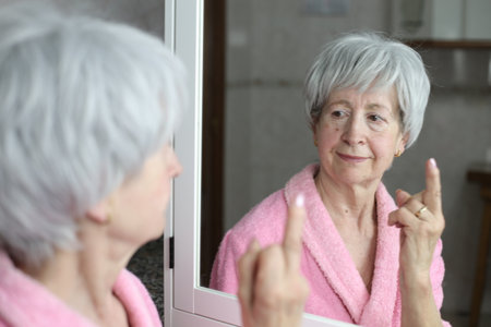 Senior woman talking to herself in front of the mirrorの写真素材