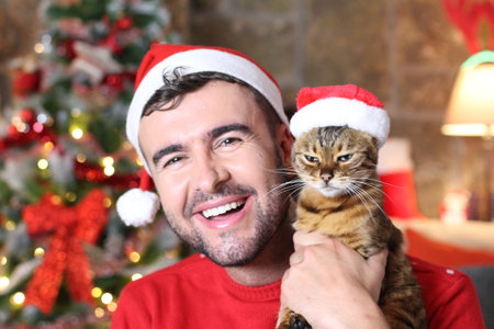 Man holding his evil cat during Christmasの写真素材