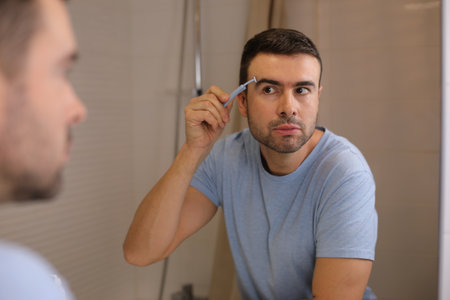 Man using special shaving tool for the surroundings of the hairy eyebrowsの写真素材