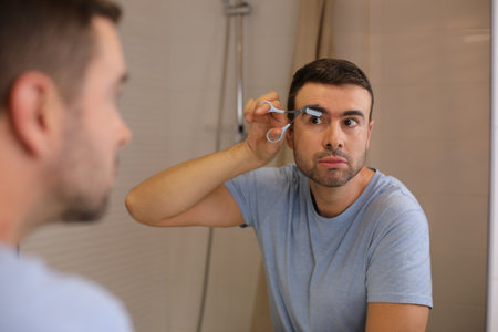 Man using special scissors than include a comb to cut his eyebrowsの写真素材