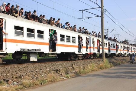 Jakarta, Indonesia, 25 February 2012 - Passengers riding on the rooftop of the commuter train.のeditorial素材