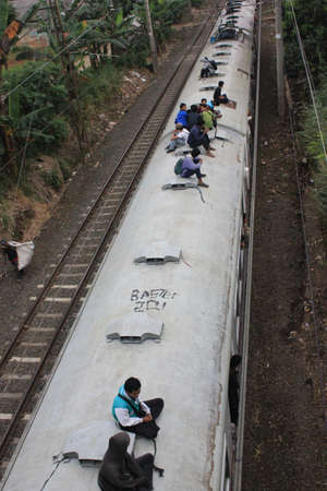 Jakarta, Indonesia, 3 March 2012 - Passengers riding on the rooftop of the commuter train 