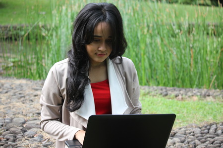 A beautiful girl typing on laptop in a gardenの写真素材