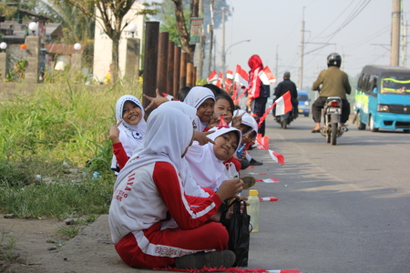 Depok, Indonesia, September 13, 2014 - Elementary school students sitting on the edge of the road to welcome the Indonesian army in order to clean up the river.のeditorial素材