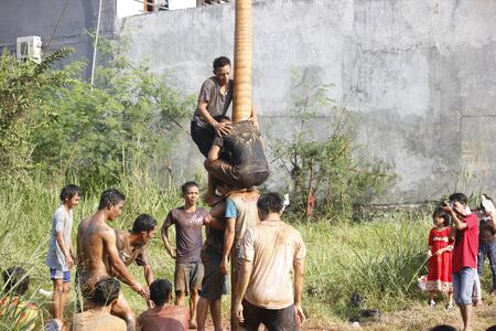 Depok, West Java, Indonesia, 17 August 2016 - Participants race to reach the peak of the pole as part the country's Independence Day celebrations in Depok, West Java, Indonesia on August 17, 2016.のeditorial素材