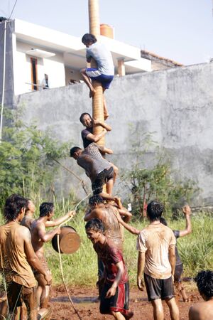 Depok, West Java, Indonesia, 17 August 2016 - Participants race to reach the peak of the pole as part the country's Independence Day celebrations in Depok, West Java, Indonesia on August 17, 2016.のeditorial素材