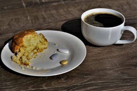 Dish with three pills, scone cake and a coffee cup. Black coffee cup, eaten scone cake, crumbs and...