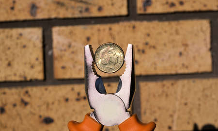 Australian dollar coin in pliers. concept of money earned by handymen or other trades professions through the use of toolsの写真素材
