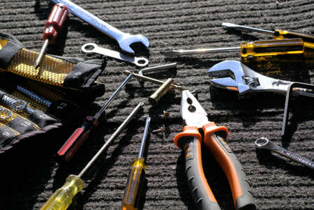 Worker's tools on gray-black work mat outdoors in direct sunlight