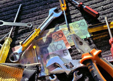 Australian dollars and Worker's tools on gray-black work mat outdoors in direct sunlightの写真素材