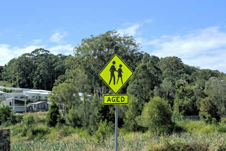 Road crossing sign for elderly people. Street sign for aged people. Yellow sign post cautioning drivers about aged crossing.の写真素材