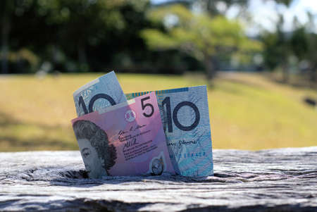 Close up of Australian money on wood. Five dollar note and ten dollar note. Dollars in outdoor...